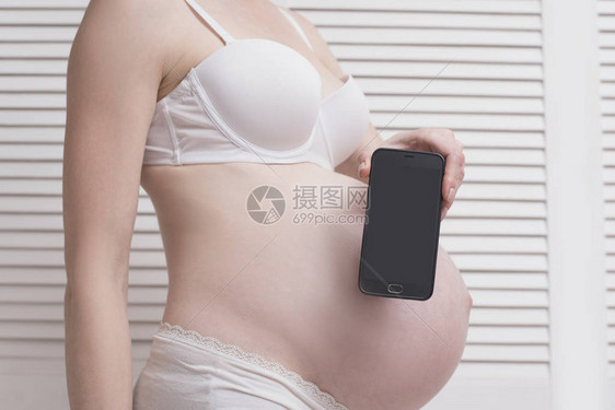 穿着内衣的孕妇持有并展示手机图片