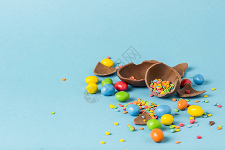 碎巧克力复活节鸡蛋和蓝色背景的多色甜食复活节背景图片