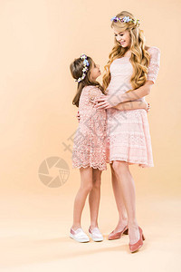 穿着优雅的蕾丝裙子和花圈的可爱女儿和漂亮的母亲图片