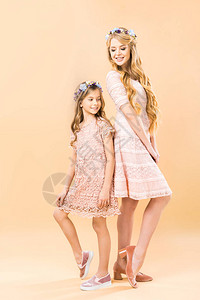 穿着优雅拉西礼服和花圈的妈和女儿背对图片