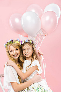 和可爱的女儿坐在一起拿着粉红背景的气球在图片