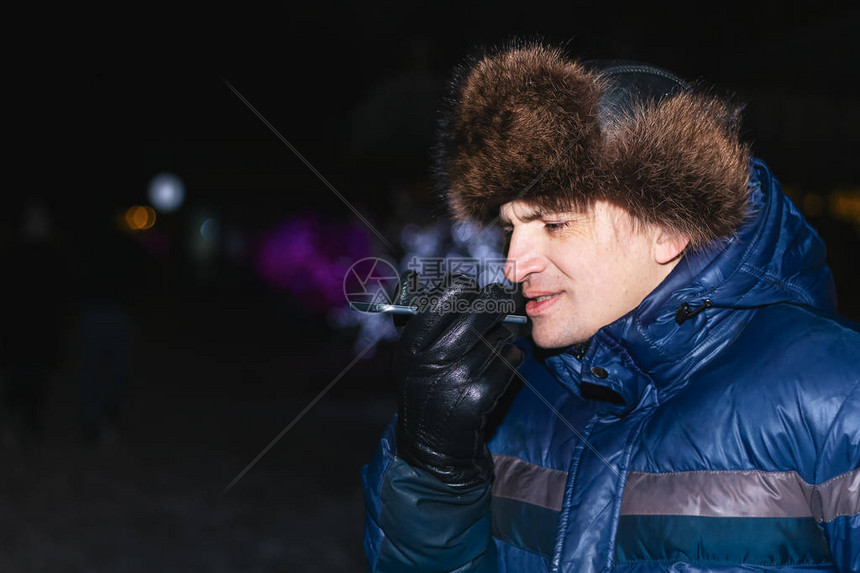 快乐的年轻人在寒冷的冬天给他的智能手机发声图片