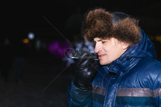 快乐的年轻人在寒冷的冬天给他的智能手机发声图片