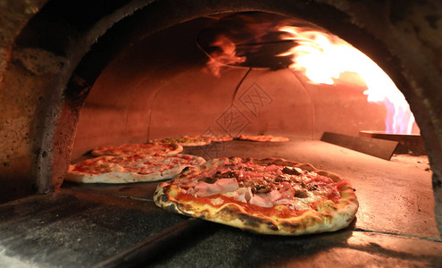 从意大利比萨饼制造厂拿起的烤炉和披萨配图片