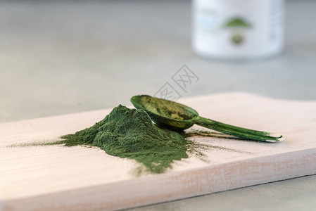 绿色螺旋藻粉木板上的健康膳食补充剂图片