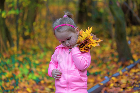 秋天公园里抱着落叶的悲伤小女孩年轻悲伤的孩子拿着叶子黑暗森林中伤心图片