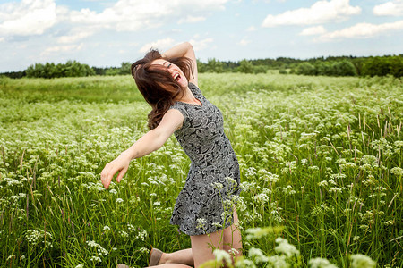 美丽的女士在夏日田上跳跃着盛开的野生花朵图片