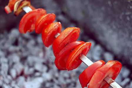 新鲜成熟的红番茄片放在火盆上方的木棍上烧烤图片
