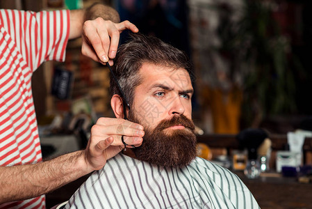 英俊的胡子男在理发店发型师在理发店服务客户是时候换新发型了使发型看起来完美年轻的胡子男背景图片