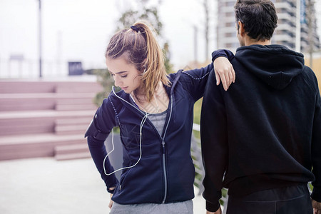 帮助青年女子在城市环境户外运动的男教图片