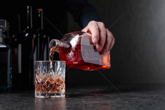 巴曼把威士忌倒在酒吧的玻璃杯里选择焦图片