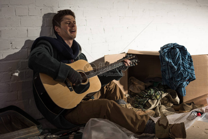无家可归的人在坐垃圾堆里弹吉他和图片