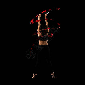 在黑色背景上用丝带做艺术体操的女人图片