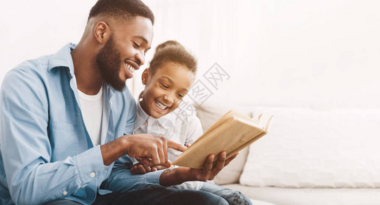 非裔美国人的爸和女儿一起在家阅读书图片