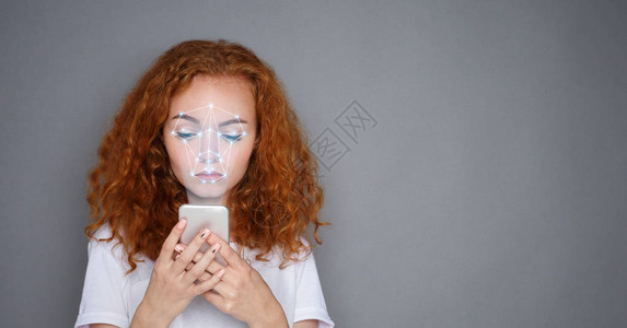 生物特征验证新的面部识别技术年轻的现代女孩手里拿着智图片