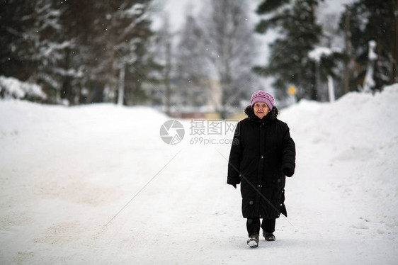 一名年长的女养恤金领取者在冬天走在图片