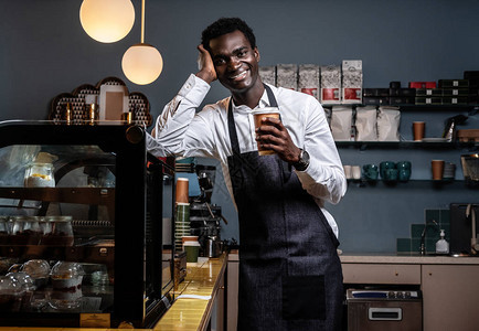 疲惫的非洲咖啡师端着一杯咖啡图片
