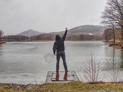 在池塘的寒冷雨天站在河边的湿人图片