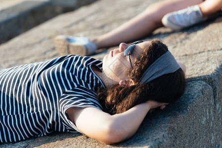 美丽的女孩的肖像躺在太阳对面的墙壁上躺着放松圣马洛图片