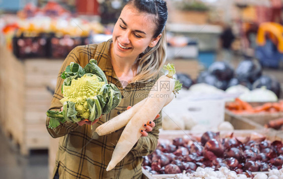 超市里的女人美丽的年轻女子拿着新鲜的有机蔬菜卷心菜和萝卜健康饮食图片