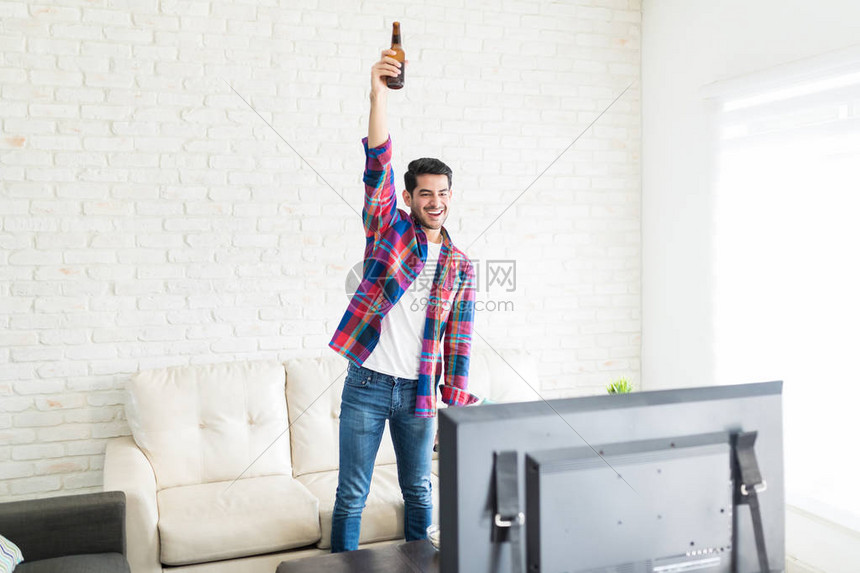 兴奋的帅哥举起啤酒瓶庆祝他最喜欢的图片