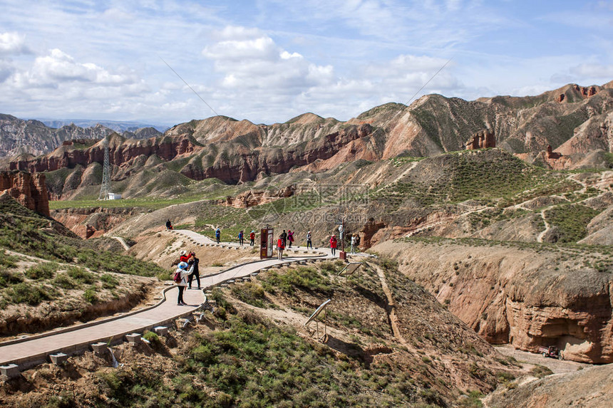游客在甘肃省苏南地区张掖冰沟丹霞峡谷地貌中行走地质公园内的红砂岩在阳光明媚的日子图片