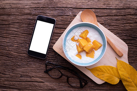 用智能手机平板电脑手机和酸奶上切片芒果的空白屏图片