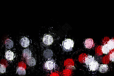 Bokeh夜间城市灯光在雨中湿玻璃后面图片