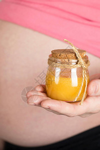 年龄在30至35岁之间的年轻怀孕妇女保留了玻璃瓶天然蜂蜜图片