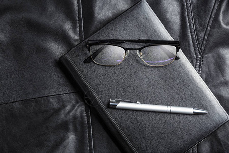 笔记本眼镜和pix在黑色皮革背景商务简约生活图片