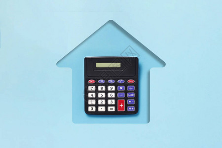 蓝纸板切割成房屋和计算器的形状购买住房抵押贷款家庭信贷规划等概念平图片