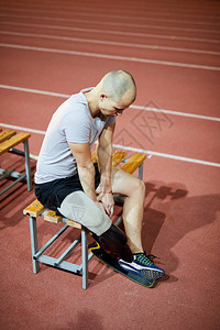 在比赛前后在体育场坐在板凳上坐着的青年残疾运动员图片
