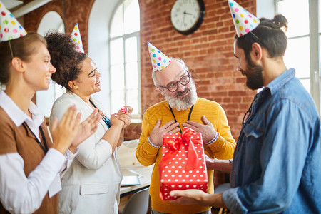 两个快乐的女商人拍掌年轻男人给老板送生日礼物图片