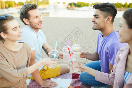 两个男人和两个女朋友喝着酒在海滩野餐图片