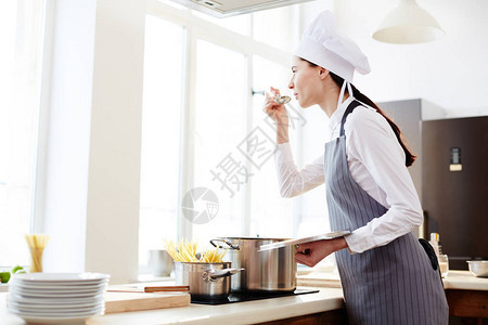 站在柜台前上岗烹饪器和配菜汤的餐桌上图片
