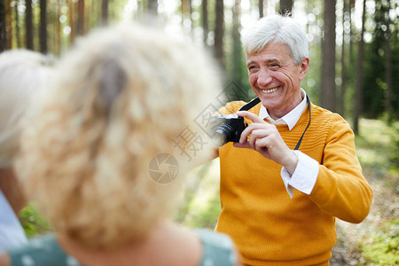 穿着黄色毛衣的英俊老人在镜头前给朋友拍照图片