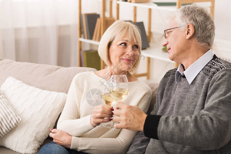 结婚纪念日双年老夫妻把葡萄酒杯连在一起图片