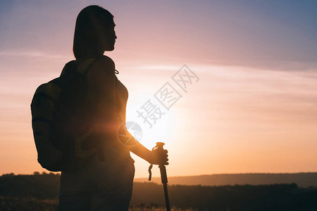 剪影徒步旅行者女人背着包和登山杖追踪图片