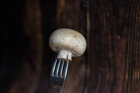 香菇油菜木制背景上叉子上的新鲜蘑菇背景
