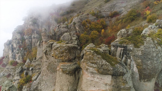 山上形状奇特的石头被雾云覆盖山中雾天的鸟瞰图和美丽的石头与黄色秋天图片