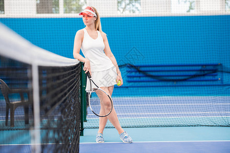 站在网球场上仰靠网复制空间的穿孔年轻图片