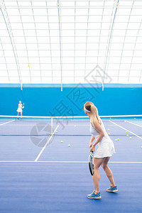 女子网球运动员在室内球场训练期间手持球拍的全长后视肖图片