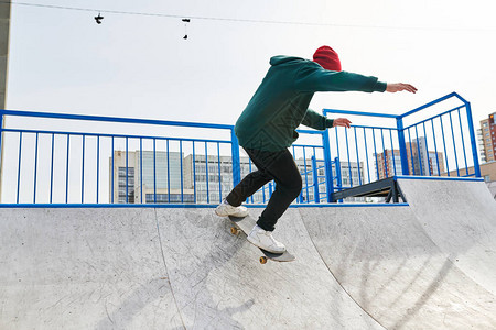 无法辨认的青年男子在极端运动公园和复制空间的坡道上玩滑板特图片