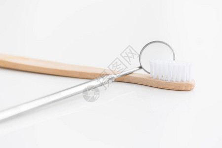 在白色背景牙科和牙齿护理概念上的简单木牙刷旁边图片