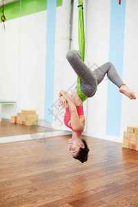 快乐的年轻女子在吊床上做空中瑜伽的肖像图片
