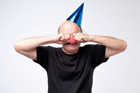 戴着生日帽的不满安的老人在派对上哭着擦眼泪图片