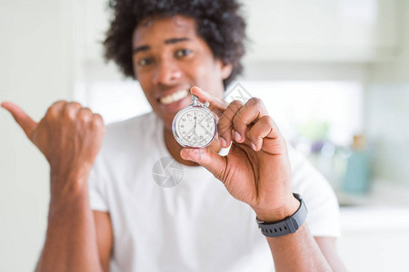 手表指着的非裔美国人男子用拇指向另一边微笑地图片