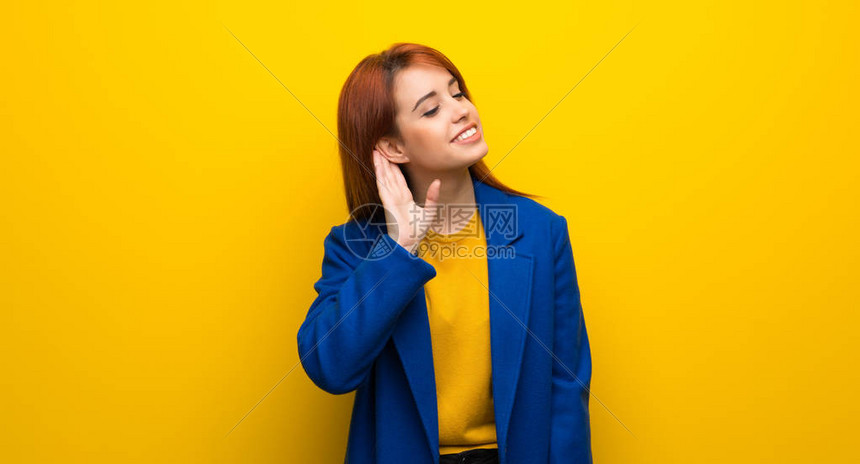 穿海沟大衣的红发年轻女人把手放在耳图片