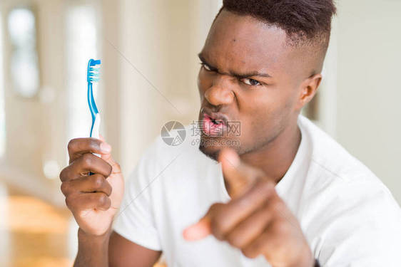持牙刷的非洲美国人用手指对着摄影机和你手牌正面的积极和自信的姿态图片