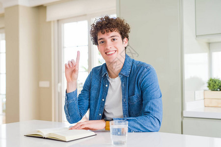 在家里读书的年轻男子惊讶于一个想法或问题用快乐的脸对着手指图片